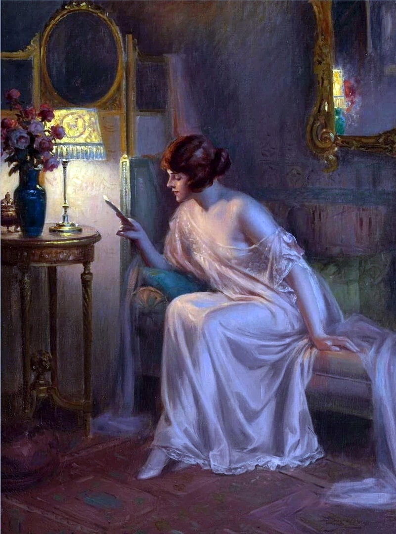 A female in an off the shoulder long pink nighty sitting on a couch reading.