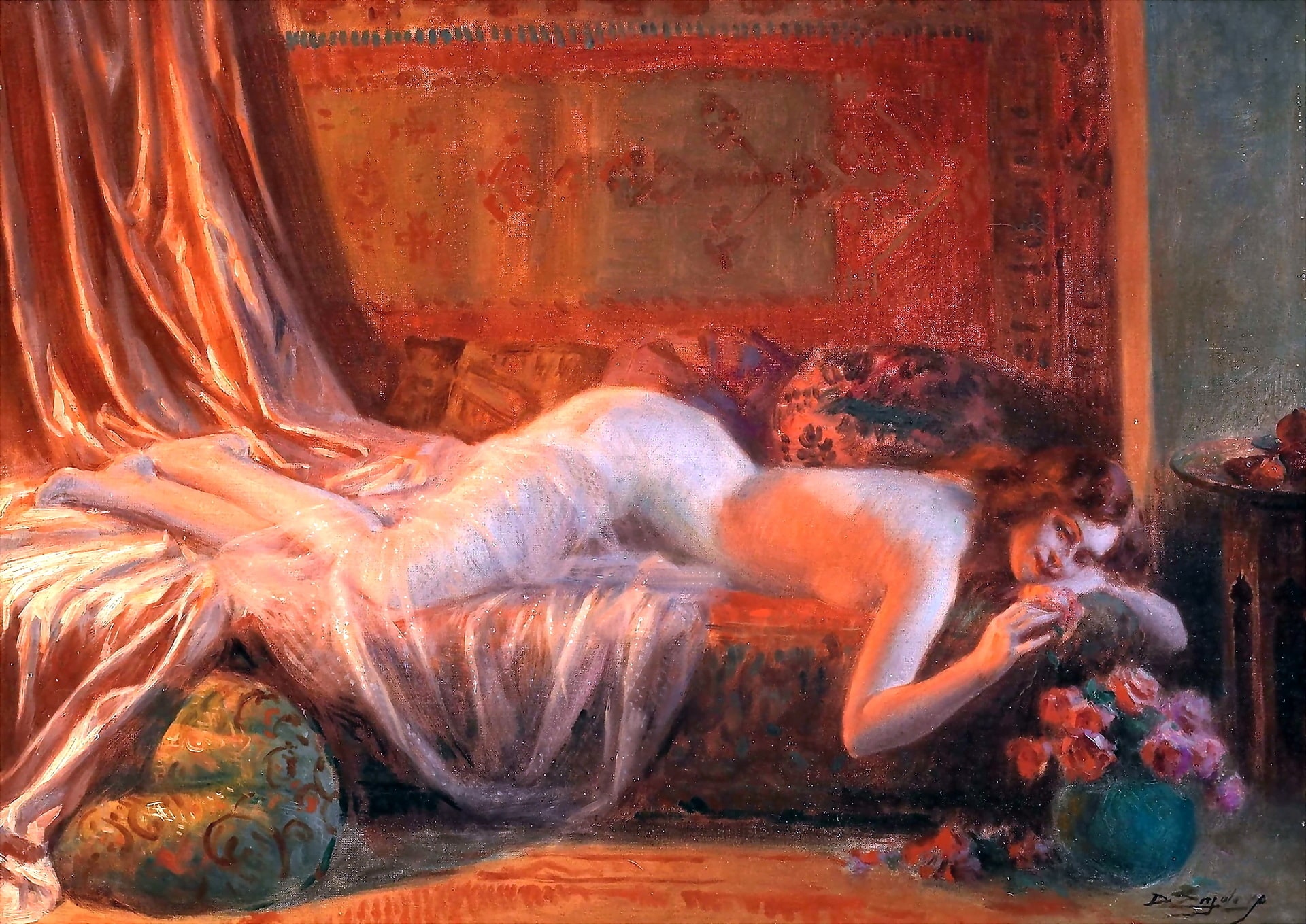 A nude woman lying on her stomach on the couch as she looks at a red rose from a vase of flowers on the floor.